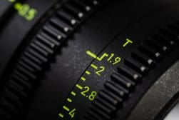 Close-up of a camera lens showing a detailed focus on the aperture ring, marked with f-stop numbers 1.9, 2, and 2.8 along with yellowish-green markings.