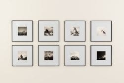 Eight framed photographs of mountains arranged in two rows on a light-colored wall.