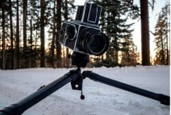 Medium format camera on a tripod in a snowy forest at dusk.