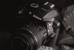 Black and white photo of a nikon dslr camera with a lens attached.