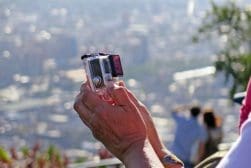 Person holding a Go Pro with a cityscape in the background.