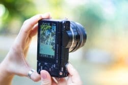 Close-up of a person holding a d Black Point-and-shoot camera with a blurred background.