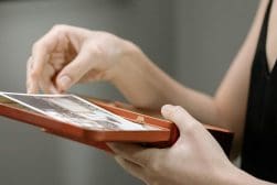 A person holds an open red box and examines photos and keepsakes inside.