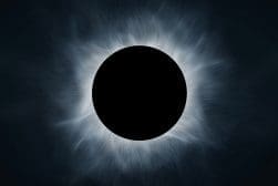 A total solar eclipse with the moon completely covering the sun, showing the sun's corona as a glowing ring against a dark sky.