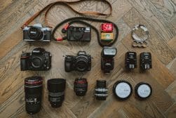 A collection of camera equipment laid out on a wooden floor.