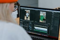 Person editing a video on a laptop using video editing software, focusing on shots of a man holding a green jacket.