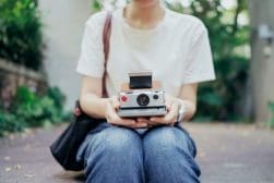 Young woman golding a vintage Polaroid camera